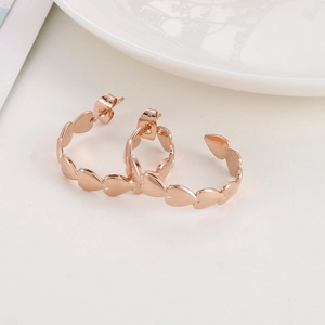 Detail of rose gold heart-shaped hoop earrings made of polished titanium steel metal