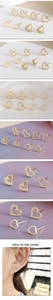 Close-up of gold-plated heart stud earrings with rhinestone inlay on purple silk fabric