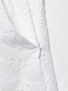 Dettaglio della cerniera invisibile su pantaloncini di cotone bianco con ricami