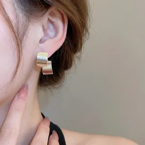Minimalist square geometric silver stud earrings with high-shine metallic finish on model