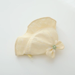 Detail of baby lace bucket hat with floral textures, bow, and a small green flower