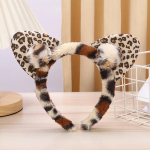 Close-up of plush leopard print and brown striped cat ear headband on a wooden surface