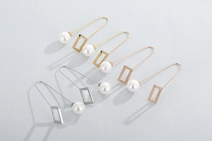 Detail view of gold and silver rectangular hoop earrings with pearls and small crystals