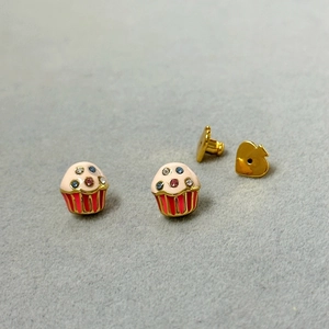 Macro shot of colorful cupcake studs with pink glaze and shiny gold heart backs