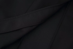 Close-up of black fabric texture and fine stitching detail on the round neck dress