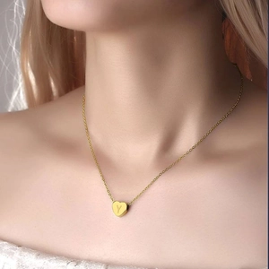 Detailed macro shot of a gold heart pendant necklace engraved with the letter Y on model