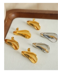 Detailed view of gold and silver irregular geometric earrings in a minimalist wood tray