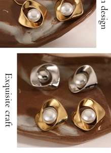 Detailed shot of twisted gold and silver pearl earrings on a ceramic dish