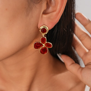 Detail view of gold floral earrings with red stones on a model in vintage style