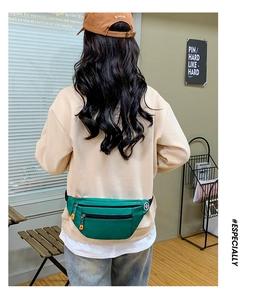 Detailed view of a green Oxford cloth waist bag with orange zippers on a model's waist