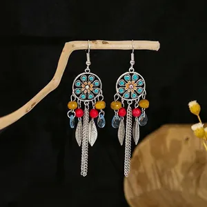 Detail of bohemian long tassel earrings with red beads and floral metal charms