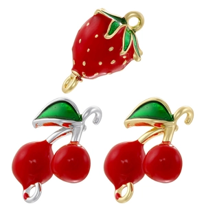 Detailed view of red strawberry and cherry enamel charms for DIY jewelry crafting