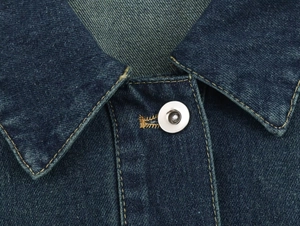 Primer plano del cuello de chaqueta vaquera azul oscuro con botones plateados y costuras