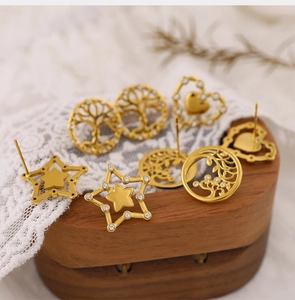 Close-up of gold hollow tree of life heart and star stud earrings with rhinestones