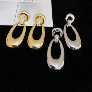 Detailed view of teardrop earrings in gold and silver with zircon-encrusted accents