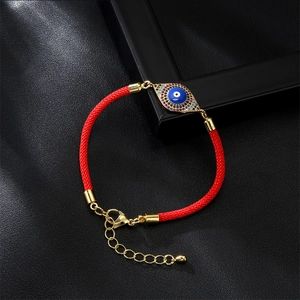Close-up of red braided Milan rope bracelet with gold evil eye charm and lobster clasp