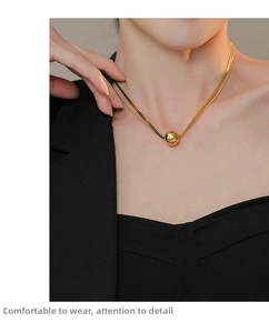 Close-up of a double-layered gold titanium necklace with a polished sphere pendant on neck