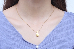 Close-up of a trendy gold-plated titanium steel guitar pendant necklace worn by a model