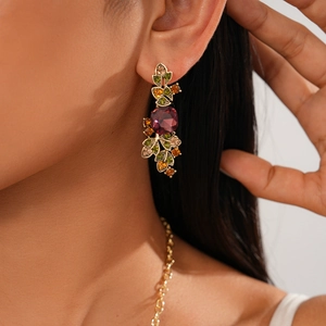 Detail of vintage palace style earring with purple gemstone and green crystal leaves