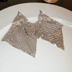 Détail macro de boucles d'oreilles nœuds géométriques en paillettes métalliques