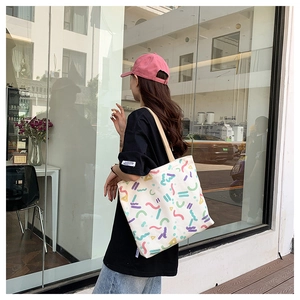 Lifestyle view of large canvas tote bag with colorful abstract geometric graffiti prints