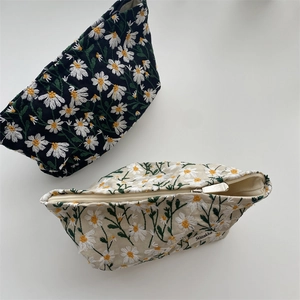 Detail of embroidered daisy flower pattern and metallic zipper on canvas cosmetic bags