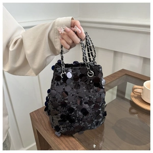 Detail of black sequined bucket bag featuring metallic chain strap and reflective texture