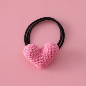 Close-up of pink handmade crochet heart hair tie with soft knit texture and elastic band