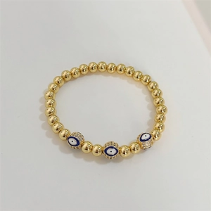 Macro shot of gold beaded evil eye bracelet with micro-pave stones on elastic band