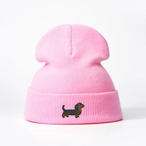 Close-up of pink knitted beanie featuring detailed dachshund embroidery and soft texture