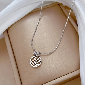 Détail macro du collier en acier titane argenté avec pendentif Fu et petite perle