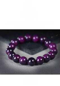 Macro shot of polished deep purple beads bracelet with reflective gloss on stone texture