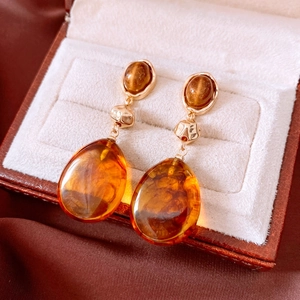 Macro shot of resin drop earrings with amber texture and hammered gold metal hardware