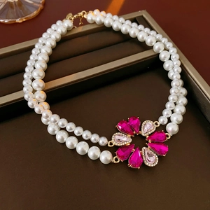Dettaglio di una collana di perle a due fili con ciondolo a fiore in pietre rosa acceso