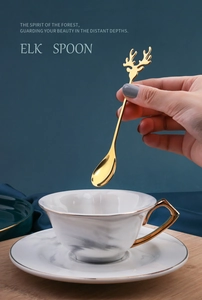 Close-up of golden elk antler coffee spoon held over a luxury marble texture cup