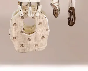 Detail of baby cotton bibs with snap buttons hanging on a multi-clip drying rack