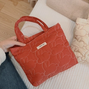 Red quilted tote bag with white rabbit stitching and simple wish label for daily use
