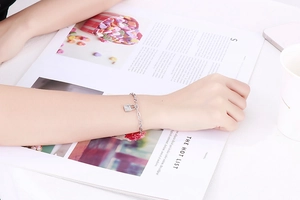 Detail of a minimalist silver chain bracelet with a padlock pendant worn by a model