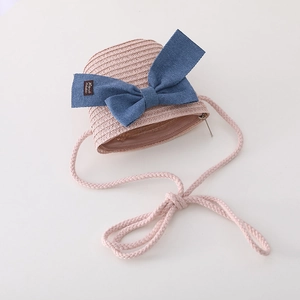 Detail of pink straw crossbody bag for kids featuring a large blue bow and zipper