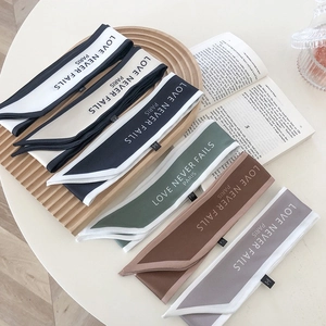 Set of six French retro silk scarves with 'Love Never Fails' text on wooden tray