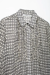 Close-up of geometric print blouse featuring elegant ruffle trim and pointed collar detail