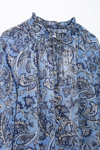 Dettaglio di top in chiffon paisley blu con colletto a balze, laccetti e bottoni bianchi