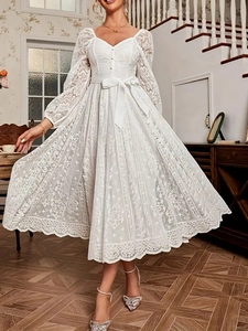 Robe élégante en dentelle blanche avec col en V, manches longues et nœud à la taille