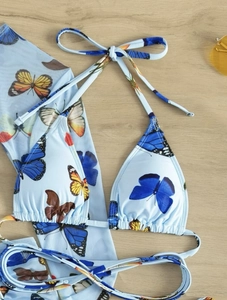 Detail of light blue bikini top featuring colorful butterfly prints and neck tie straps