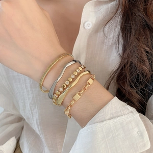 Close-up of stacked 18k gold plated bracelets with honeycomb pattern and zircon inlay