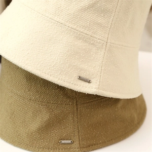 Detailed close-up of twill fabric texture and metal logo on casual bucket hats