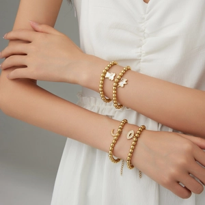 Golden beaded bracelets featuring unicorn, bear, and moon pendants worn by a model