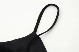 Detail shot of the adjustable black spaghetti strap on a slim fit deep V-neck dress