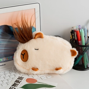 Macro detail of plush Capybara pencil case with messy hair design on laptop keyboard
