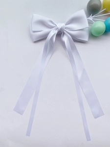 Dettaglio macro del fermaglio a fiocco in raso bianco con nastri lunghi eleganti
